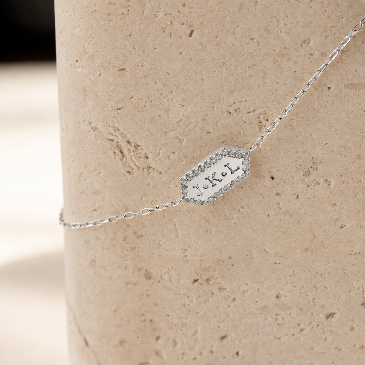 Silver necklace with a pendant on a beige stone surface